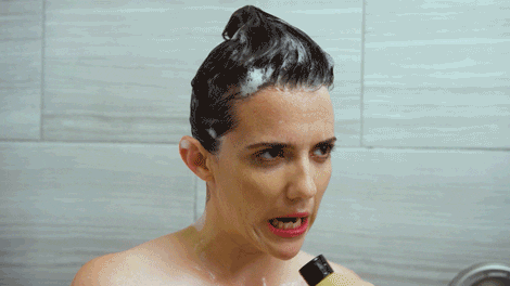 Mulher canta com seu shampoo enquanto lava o cabelo